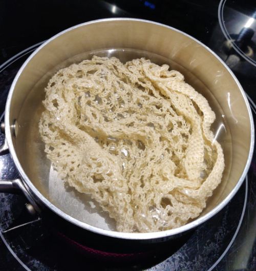 A cream colored marketbag in a pot of water